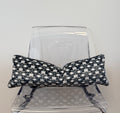 Black and white patterned pillow on a clear plastic chair against a light gray background