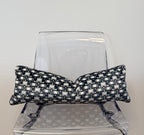 Black and white patterned pillow on a clear plastic chair against a light gray background