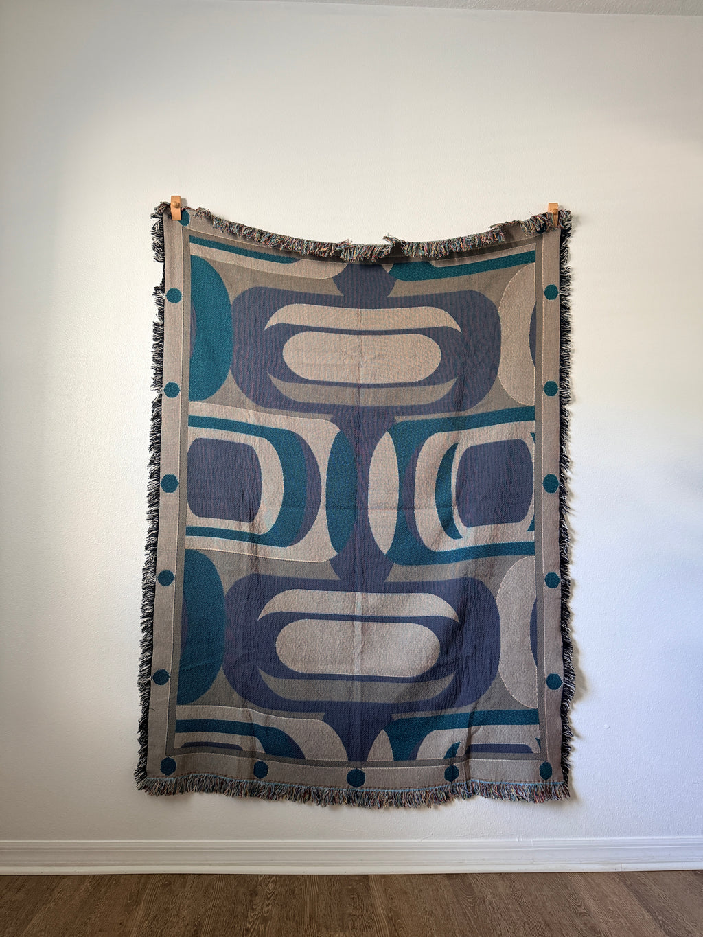 Decorative blanket with geometric pattern  against a white wall.