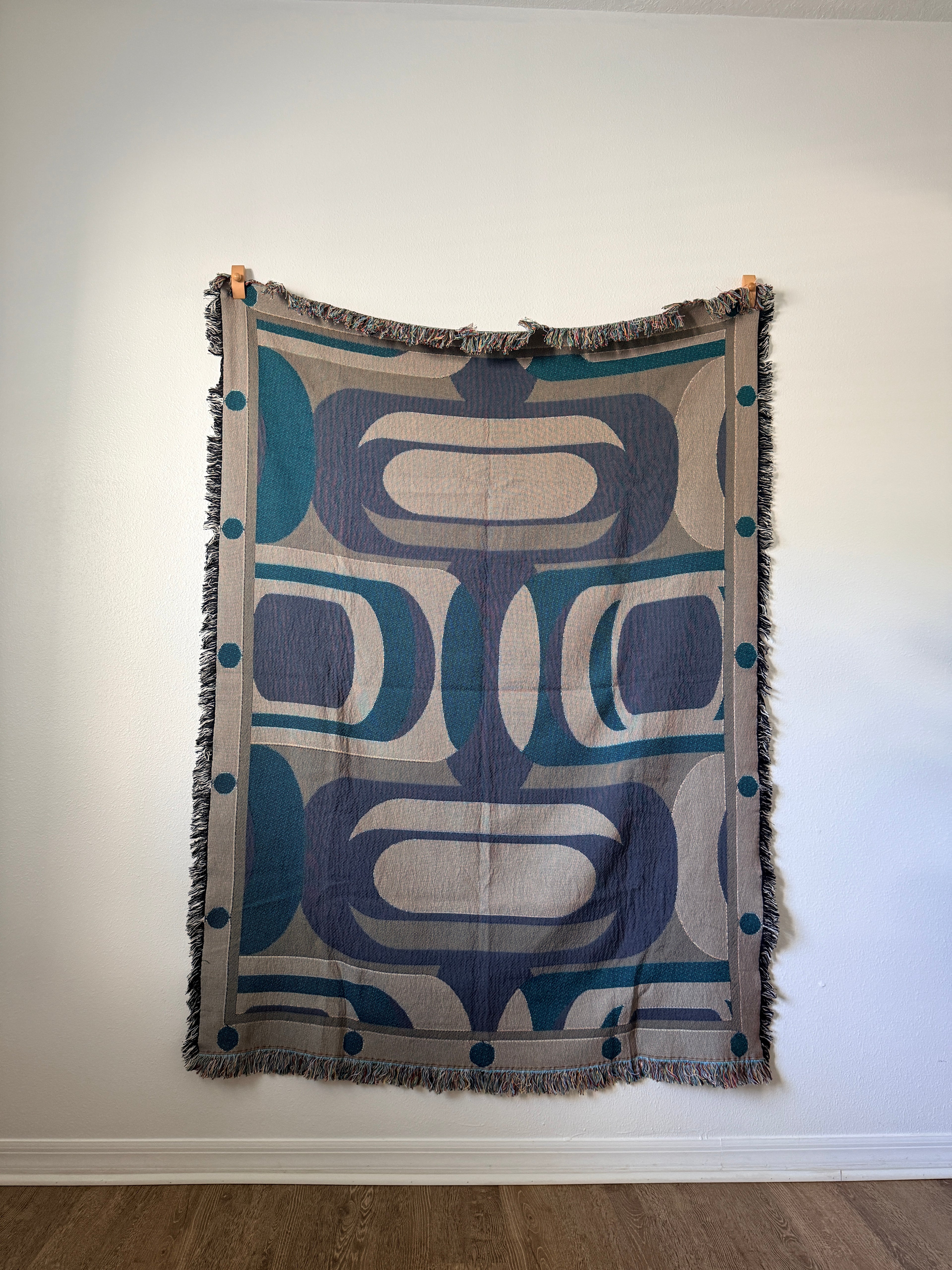 Decorative blanket with geometric pattern  against a white wall.