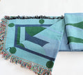 Woven green and blue blanket with geometric pattern on a white background