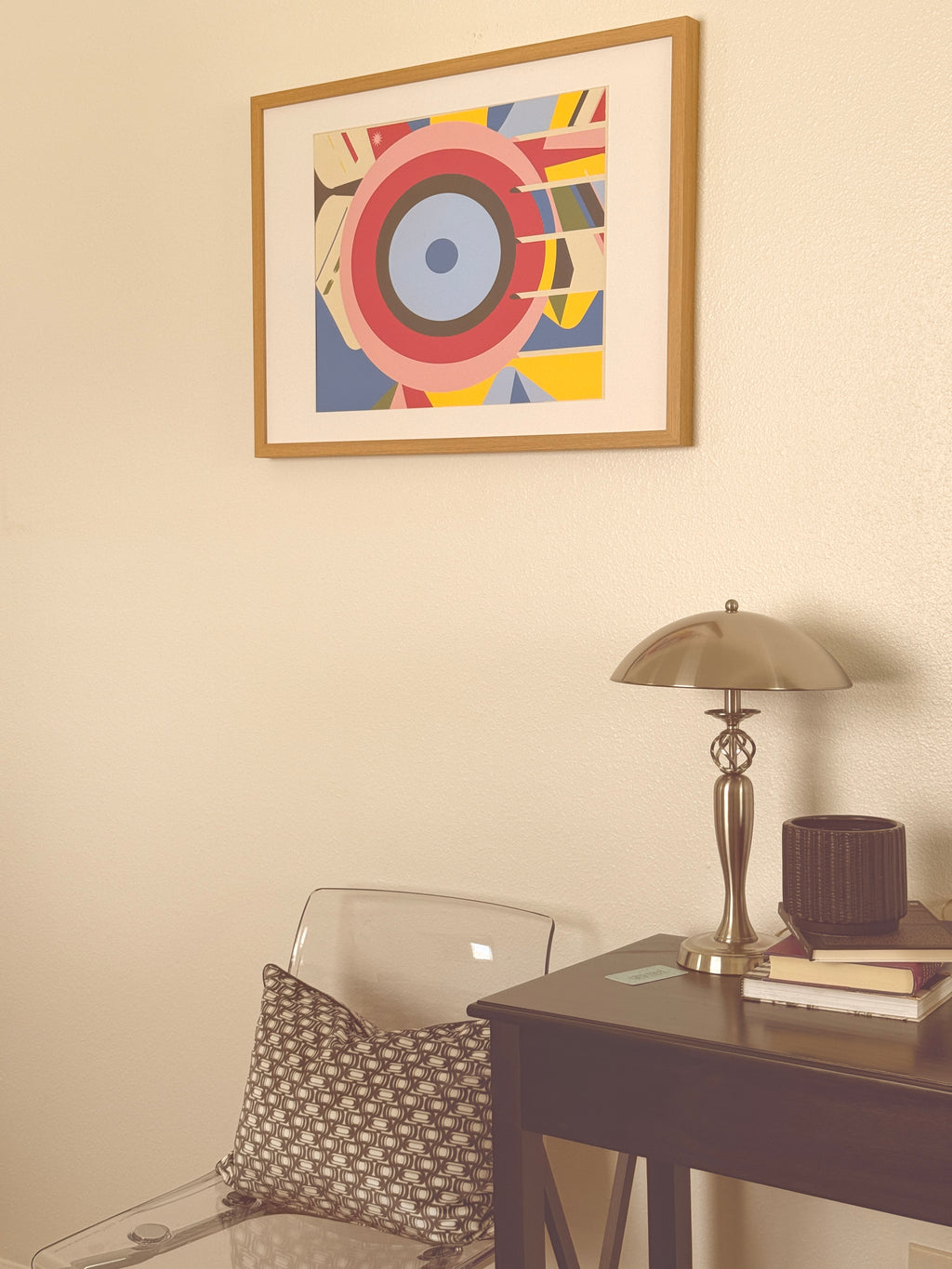 Colorful abstract art on a wall with a lamp and mirror in the background.