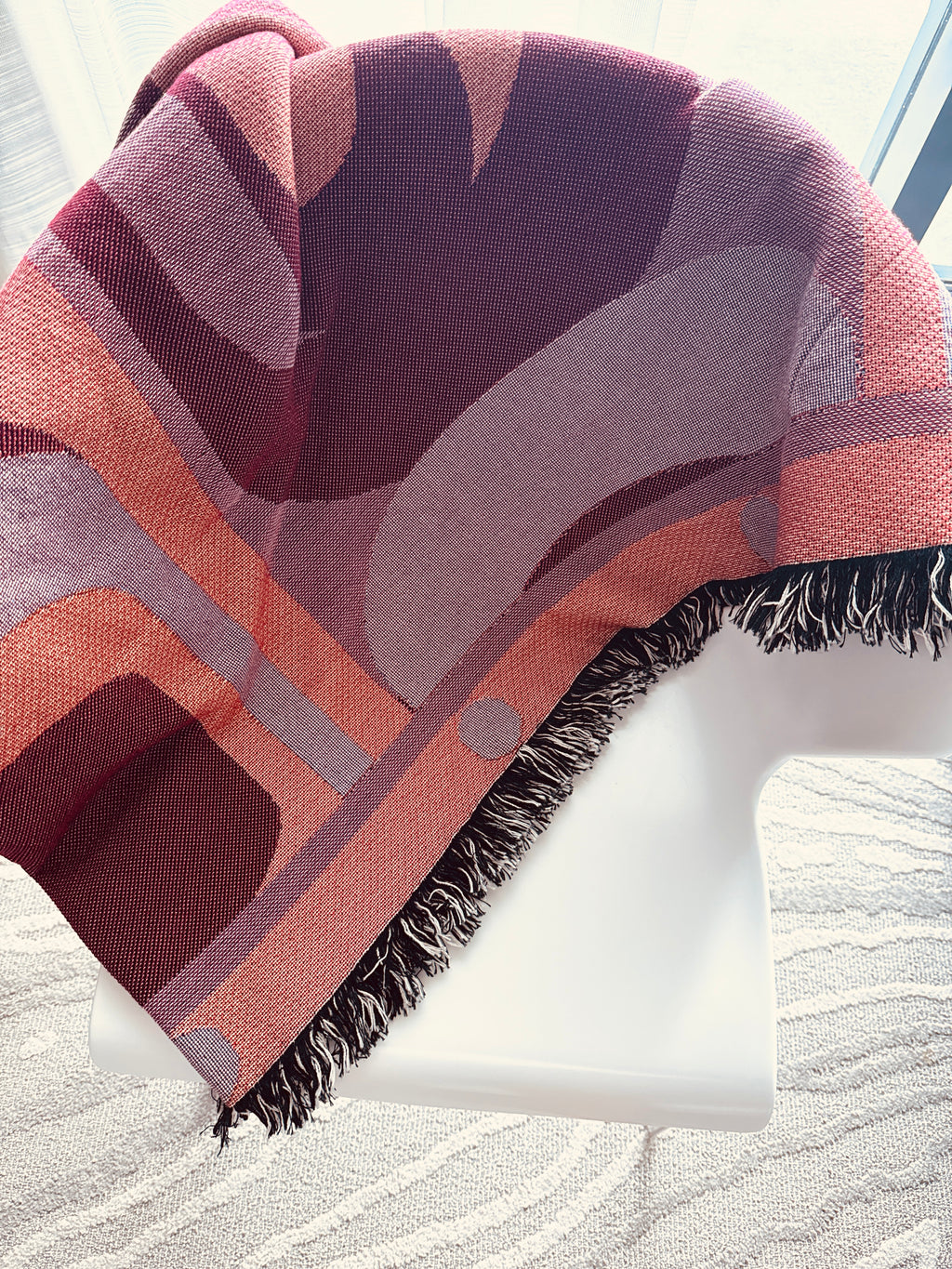Patterned throw blanket draped over a chair with a neutral background