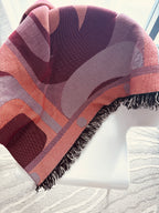 Patterned throw blanket draped over a chair with a neutral background