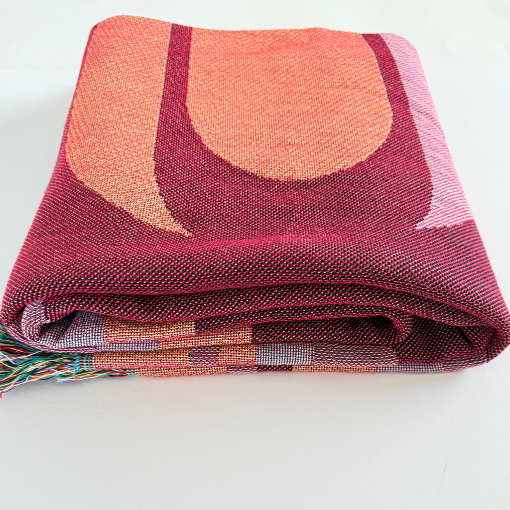 Folded patterned blanket with geometric design on a white background