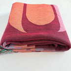 Folded patterned blanket with geometric design on a white background