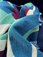 Multicolored woven throw blanket draped over person traveling in a car 