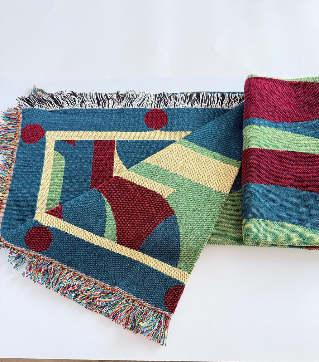 Colorful geometric-patterned blanket and striped fabric on a white surface
