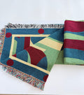 Colorful geometric-patterned blanket and striped fabric on a white surface