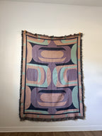 Decorative blanket with geometric pattern hanging on a white wall