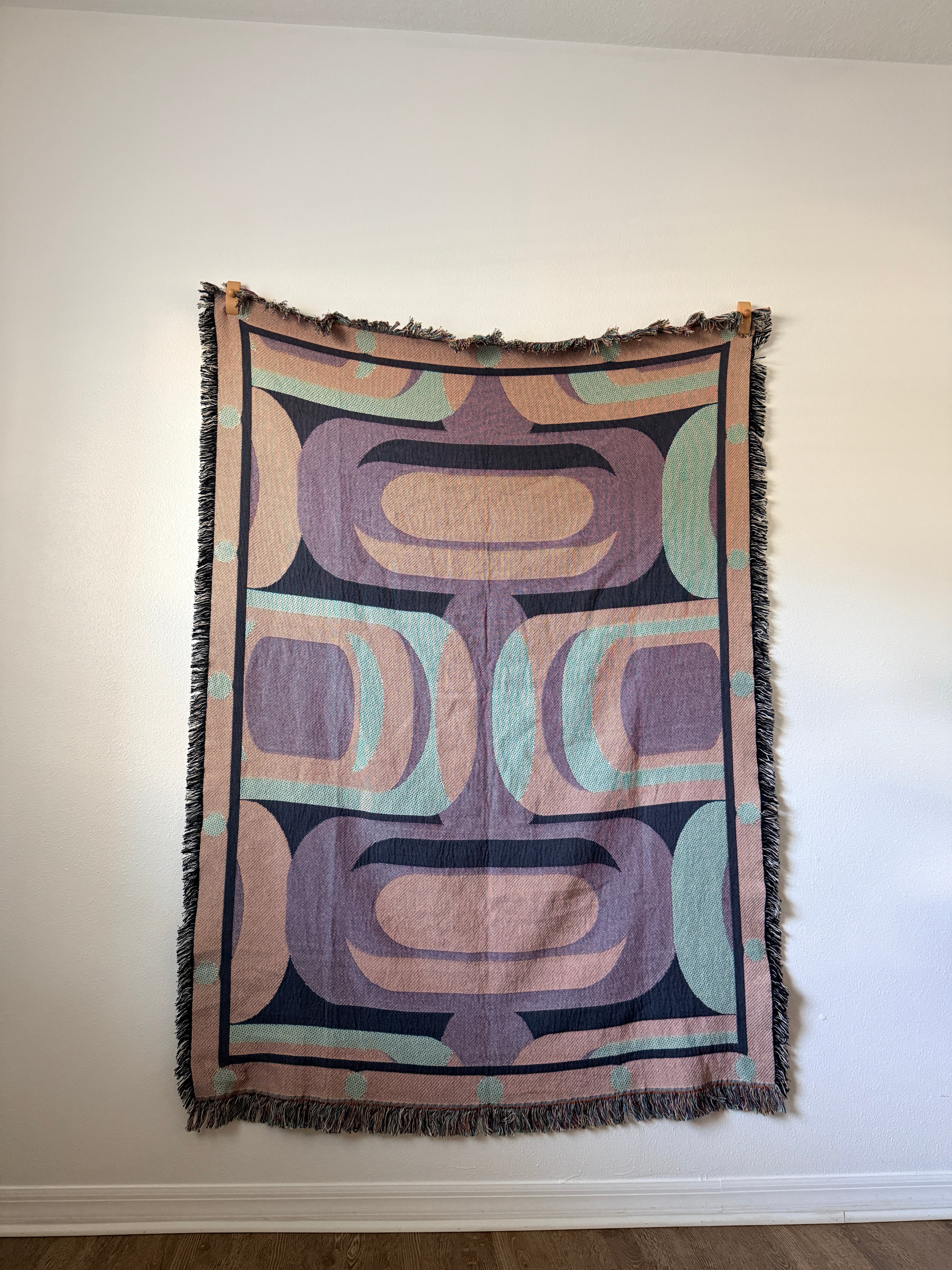 Decorative blanket with geometric pattern hanging on a white wall